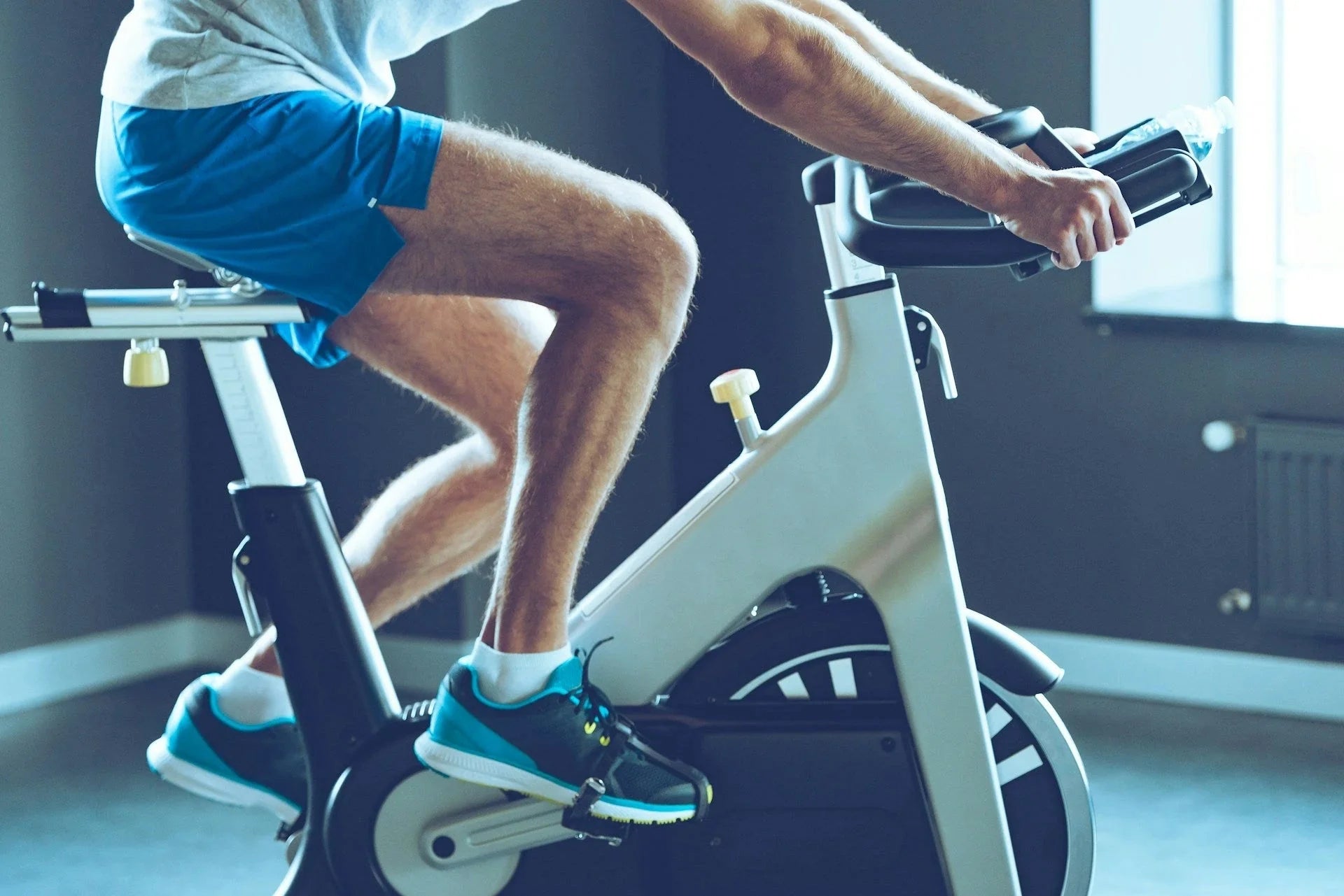 Person pedalling a stationary exercise bike in a bright home gym showcasing exercise bikes for home workouts